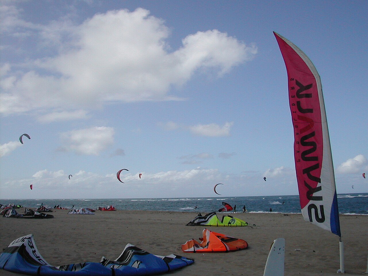 Kitesurfing kites in the sky over a windy beach at Cabarete with equipment laid out on the sand