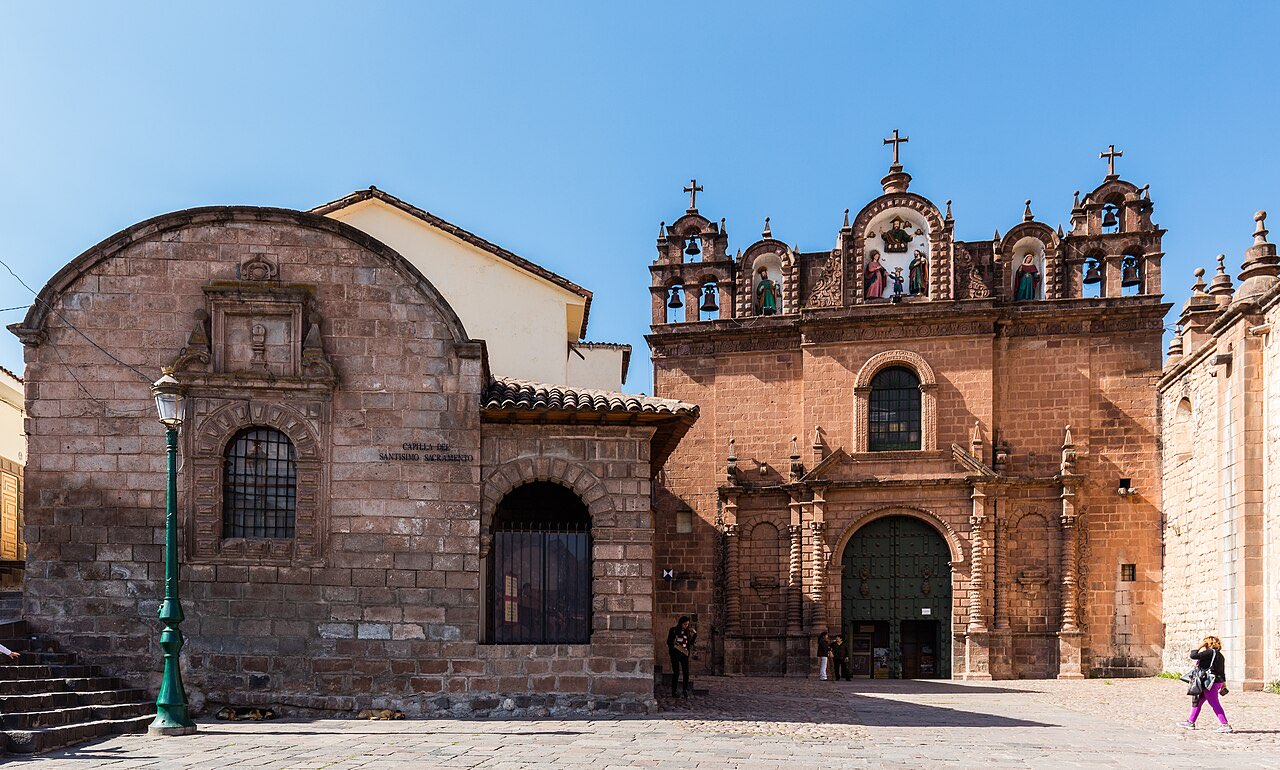 The stone facade of Cusco cathedral on the Plaza de Armas under a clear blue sky
