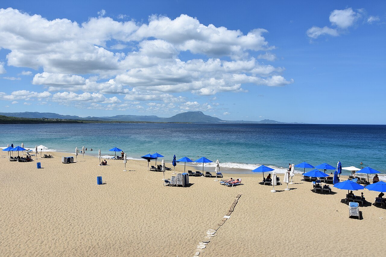 Playa Alicia at Sosua with blue parasols on pale sand and calm turquoise water
