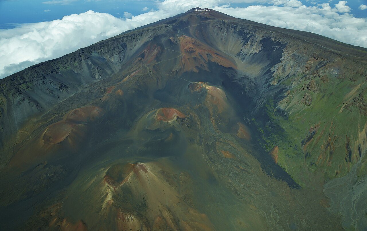 Aerial view of the cinder cones and eroded basin inside the summit crater of Haleakala, with cloud banked against the rim